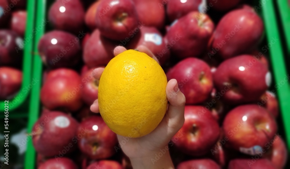 Fresh lemon with blurred red apples background Fresh lemon with blurred red apples background