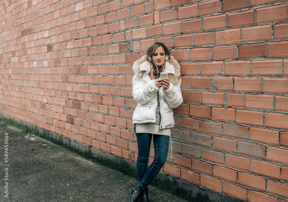 young woman with headphones on brick wall young woman with headphones on brick wall