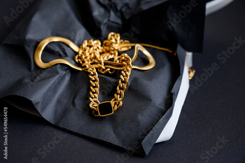 Various gold jewelry. Gold large chain. Long, wide chain on a black background.