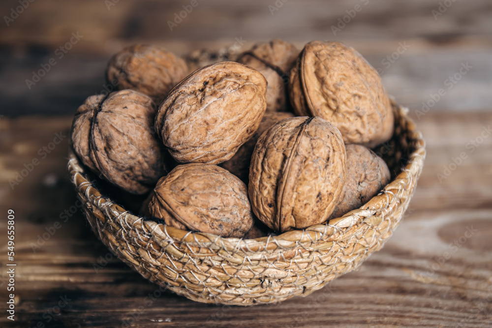 Close-up, whole walnuts in a wicker bowl on a wooden background. Close-up, whole walnuts in a wicker bowl on a wooden background.