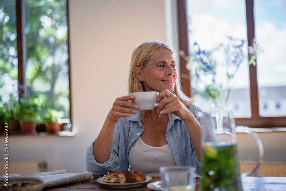 Mature woman holding cup of coffee at home Mature woman holding cup of coffee at home