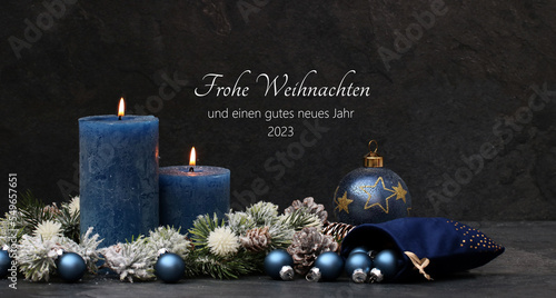 Slika na platnu Weihnachtskarte: Elegante Weihnachtsdekoration mit Kerzen und Weihnachtskugeln in den Farben blau und schwarz mit Text Frohe Weihnachten und ein gutes neues Jahr 2023