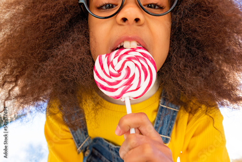 Girl with buck teeth eating lollipop photo