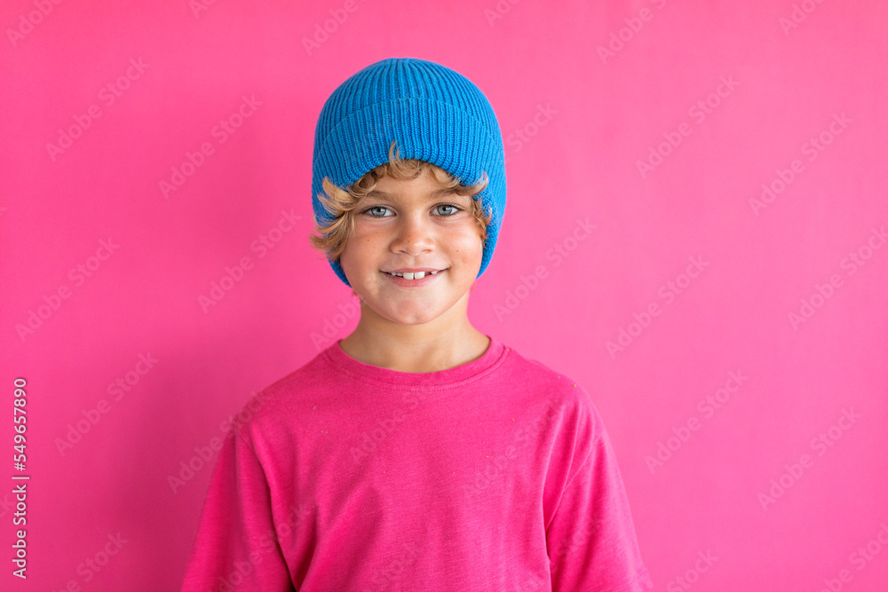 Smiling boy wearing blue knit hat against pink background Smiling boy wearing blue knit hat against pink background