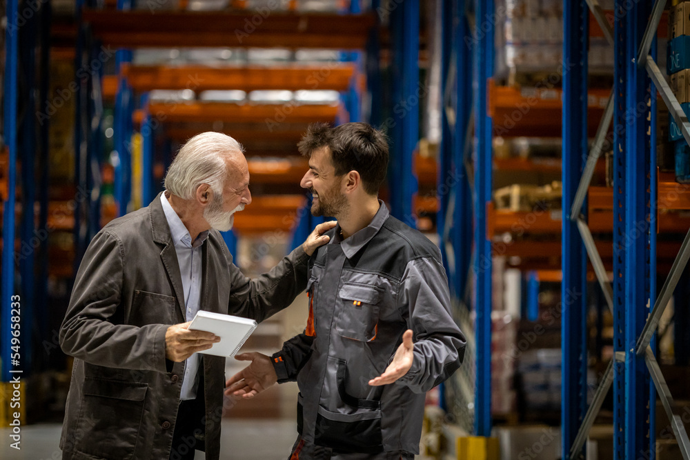 Warehouse manager and worker smiling and talking about work