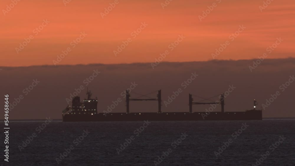 A huge cargo ship floats on the sea in the yellow rays of the afternoon sun. A huge cargo ship floats on the sea in the yellow rays of the afternoon sun.