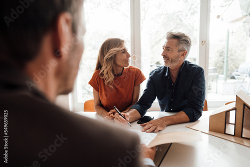 Mature couple signing contract with real estate agent photo