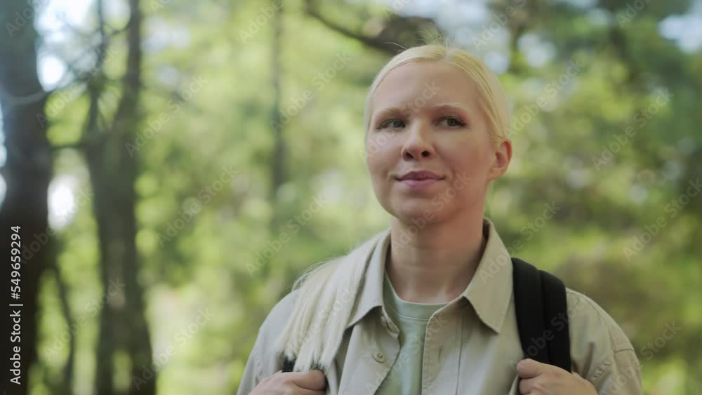 Slow-motion close-up of an attractive happy smiling woman walking through the forest on a sunny day with a briefcase. A female tourist walks through a summer forest in the rays of the sun. 4k footage Slow-motion close-up of an attractive happy smiling woman walking through the forest on a sunny day with a briefcase. A female tourist walks through a summer forest in the rays of the sun. 4k footage