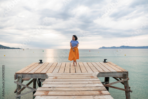 Thoughtful woman standing on jetty photo