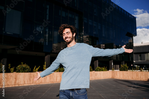 Carefree young man with arms outstretched enjoying in front of building photo