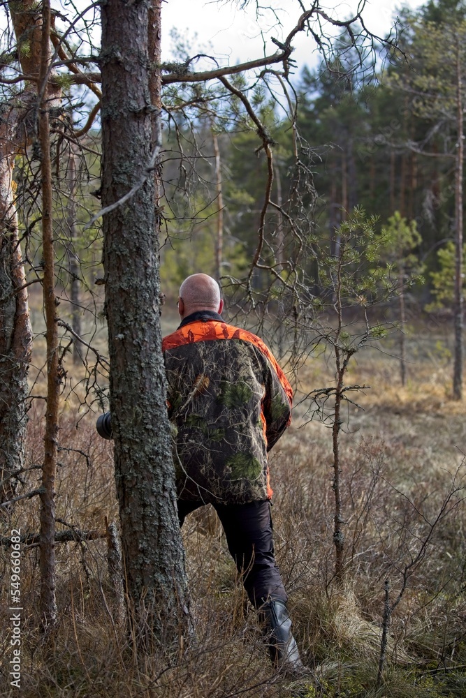 A man sneaks into the forest with his camera in search of herons