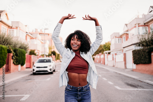 Happy woman with arms raised enjoying dancing on road photo