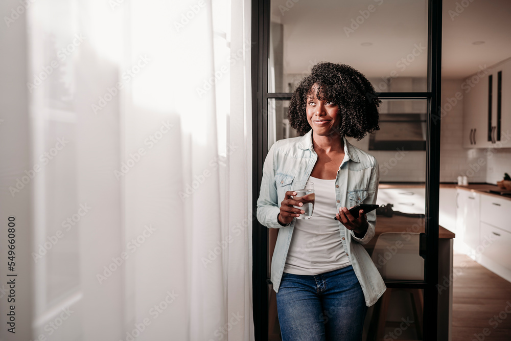 Smiling woman holding smart phone and glass of water at home Smiling woman holding smart phone and glass of water at home