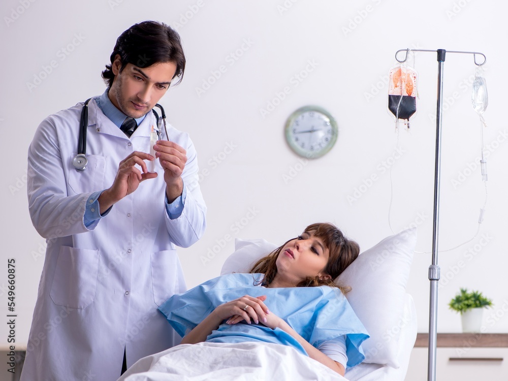 Naklejka premium Male doctor visiting female patient in ward