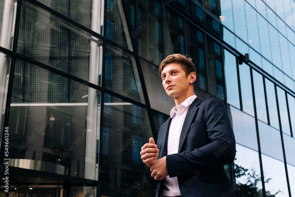 Contemplative businessman standing in front of building Contemplative businessman standing in front of building