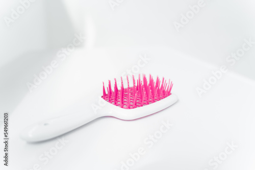 white comb with pink teeth for hair extensions hair on isolated background