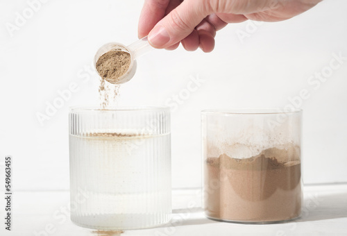 woman pouring plant based protein powder into a glass of water. plant protein as food supplement, bones and joints health support.