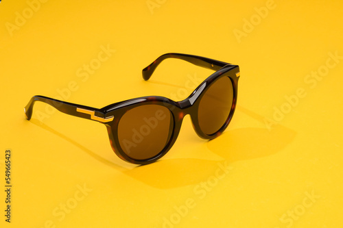 Fashion sunglasses in sunlight on summer yellow background. Woman stylish eyeglasses for banner