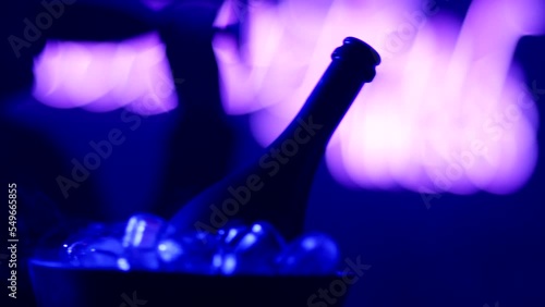 Close up view of sexy woman flirting , dancing and drinking glass of champagne . Smoke rises from ice cubes . Black colored sparkling wine bottle and glasses inside night club . Concept of nightlife