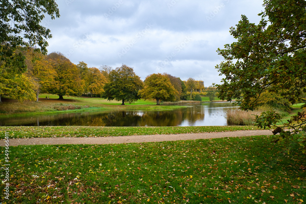Frederiksborg Castle Park in autumn with mighty deciduous, landscaped lake.