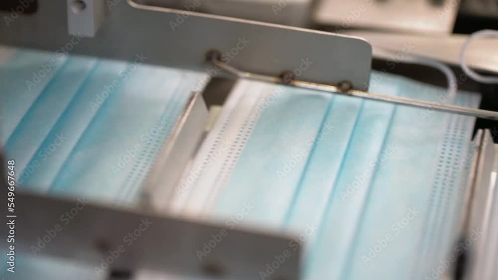 Closeup process of medical face masks being made in a factory. Automated machinery making respiratory medical masks in large quantities. Closeup process of medical face masks being made in a factory. Automated machinery making respiratory medical masks in large quantities.