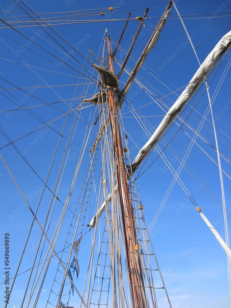 Mast of an old sailing ship with a folded sail and ropes Mast of an old sailing ship with a folded sail and ropes