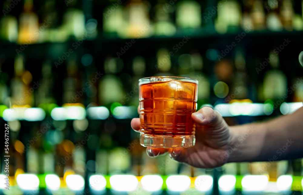 hand holding a glass of coktail in a bar - obrazy, fototapety, plakaty 