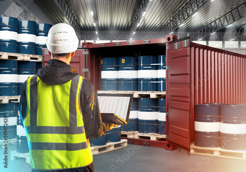 Warehouse Supervisor. Inspector is man with his back to camera. Guy with laptop looks at barrels. Sea container with barrels inside warehouse. Man storekeeper controls delivery. Audit, revision