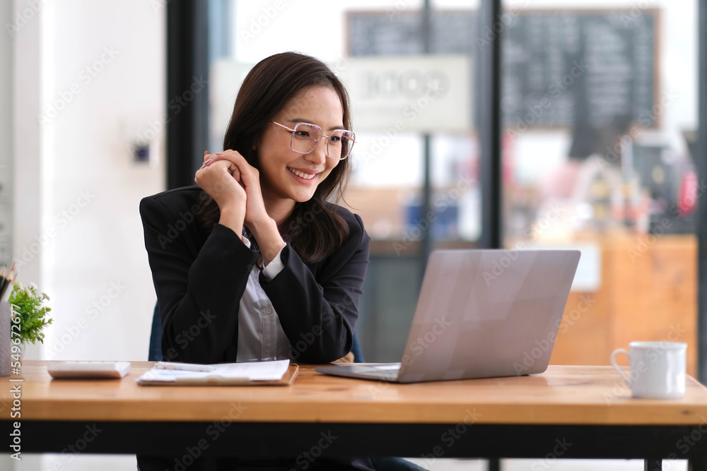 Portrait of happy business woman wearing glasses at workplace in office. Young handsome female worker using modern laptop Portrait of happy business woman wearing glasses at workplace in office. Young handsome female worker using modern laptop