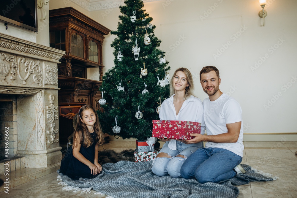 family opens presents near the Christmas tree