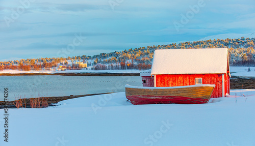 Foto Beautiful winter landscape with old fishing red cabin (boathouse) boat at sunset