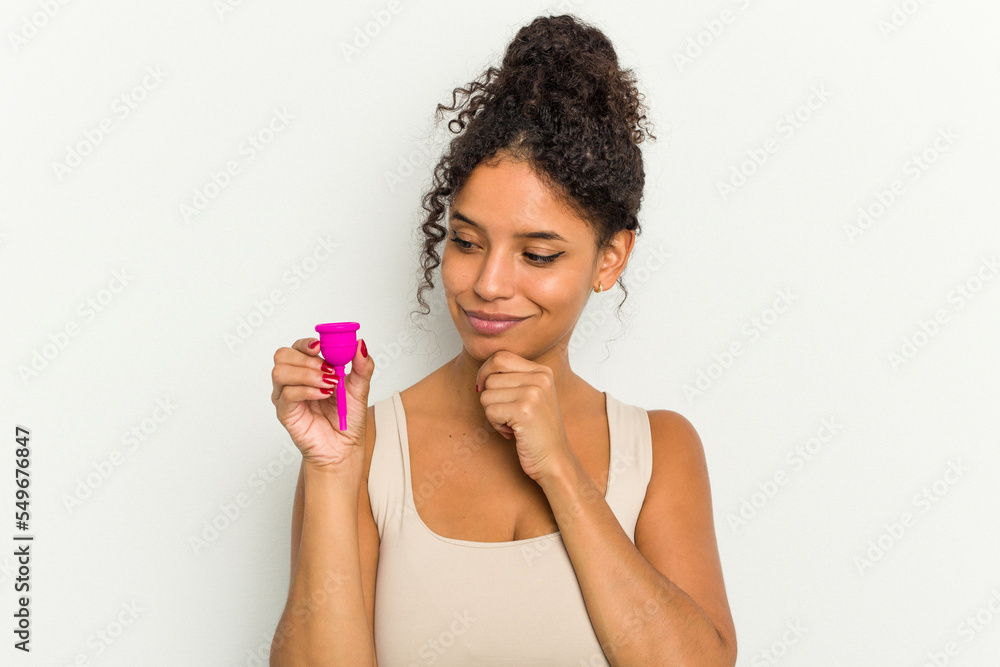 Young brazilian woman holding a menstrual cup isolated looking sideways with doubtful and skeptical expression. Young brazilian woman holding a menstrual cup isolated looking sideways with doubtful and skeptical expression.