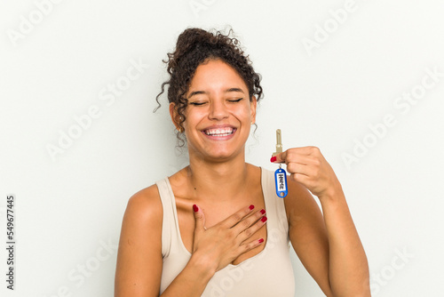 Young brazilian woman holding home keys isolated laughs out loudly keeping hand on chest.