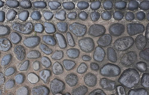 River stones pressed into concrete pavement background and wallpaper texture