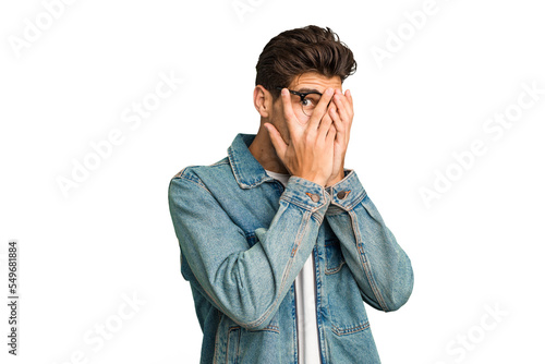 Young caucasian handsome man isolated blink through fingers frightened and nervous.
