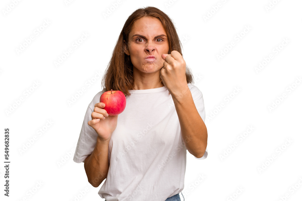 Young caucasian woman holding a red apple isolated showing fist to camera, aggressive facial expression. Young caucasian woman holding a red apple isolated showing fist to camera, aggressive facial expression.