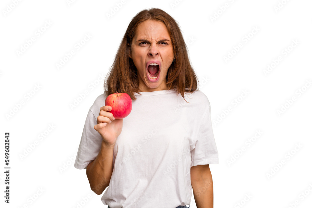 Young caucasian woman holding a red apple isolated screaming very angry and aggressive. Young caucasian woman holding a red apple isolated screaming very angry and aggressive.
