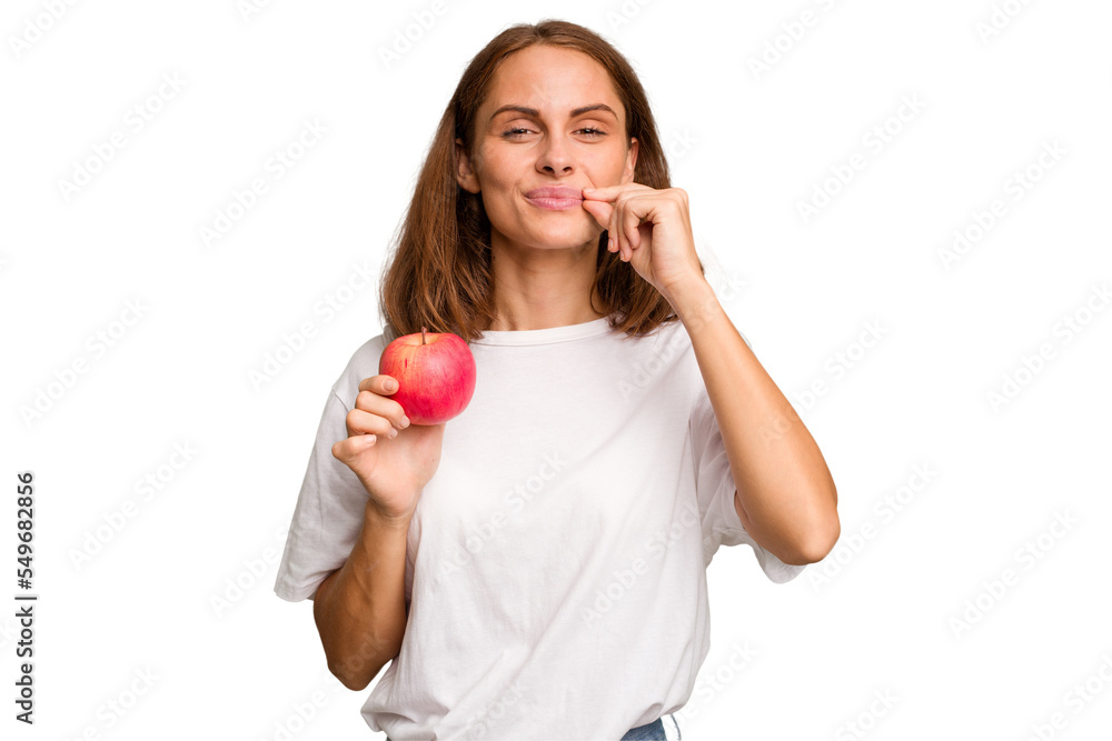 Young caucasian woman holding a red apple isolated with fingers on lips keeping a secret. Young caucasian woman holding a red apple isolated with fingers on lips keeping a secret.