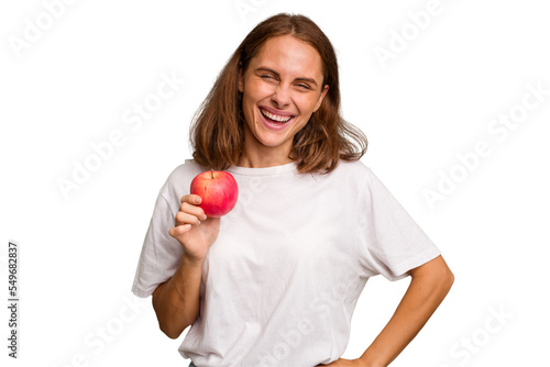 Young caucasian woman holding a red apple isolated laughing and having fun.