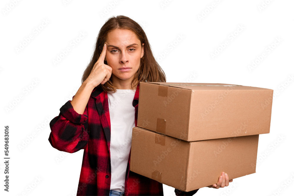 Young caucasian woman moving while picking up a box full of things isolated pointing temple with finger, thinking, focused on a task. Young caucasian woman moving while picking up a box full of things isolated pointing temple with finger, thinking, focused on a task.