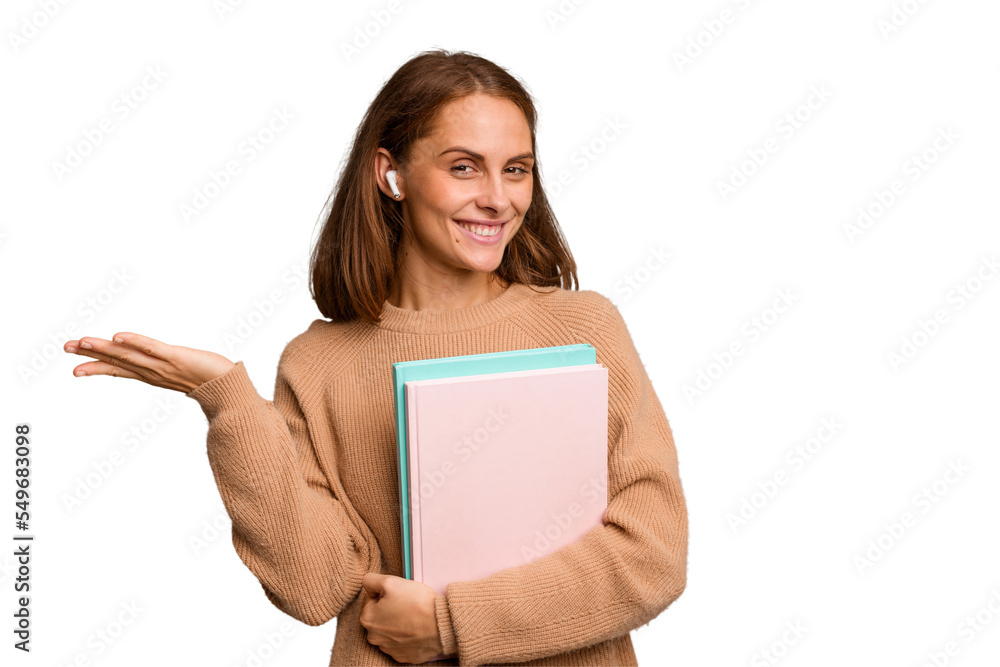 Young student woman holding a books isolated showing a copy space on a palm and holding another hand on waist. Young student woman holding a books isolated showing a copy space on a palm and holding another hand on waist.