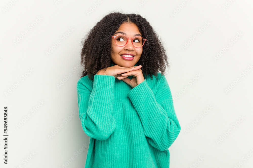 Young african american woman isolated on white background keeps hands under chin, is looking happily aside. Young african american woman isolated on white background keeps hands under chin, is looking happily aside.