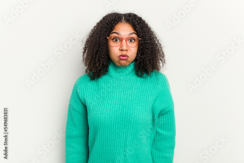 Young african american woman isolated on white background blows cheeks, has tired expression. Facial expression concept. © Asier