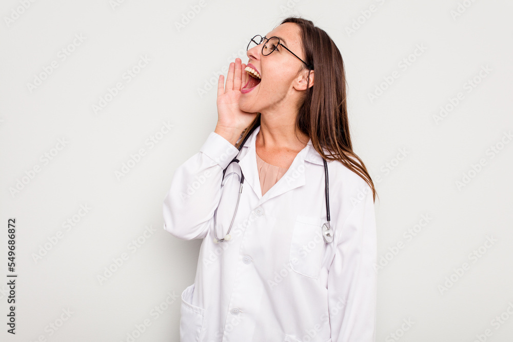 Young doctor woman isolated on white background shouting and holding palm near opened mouth. Young doctor woman isolated on white background shouting and holding palm near opened mouth.