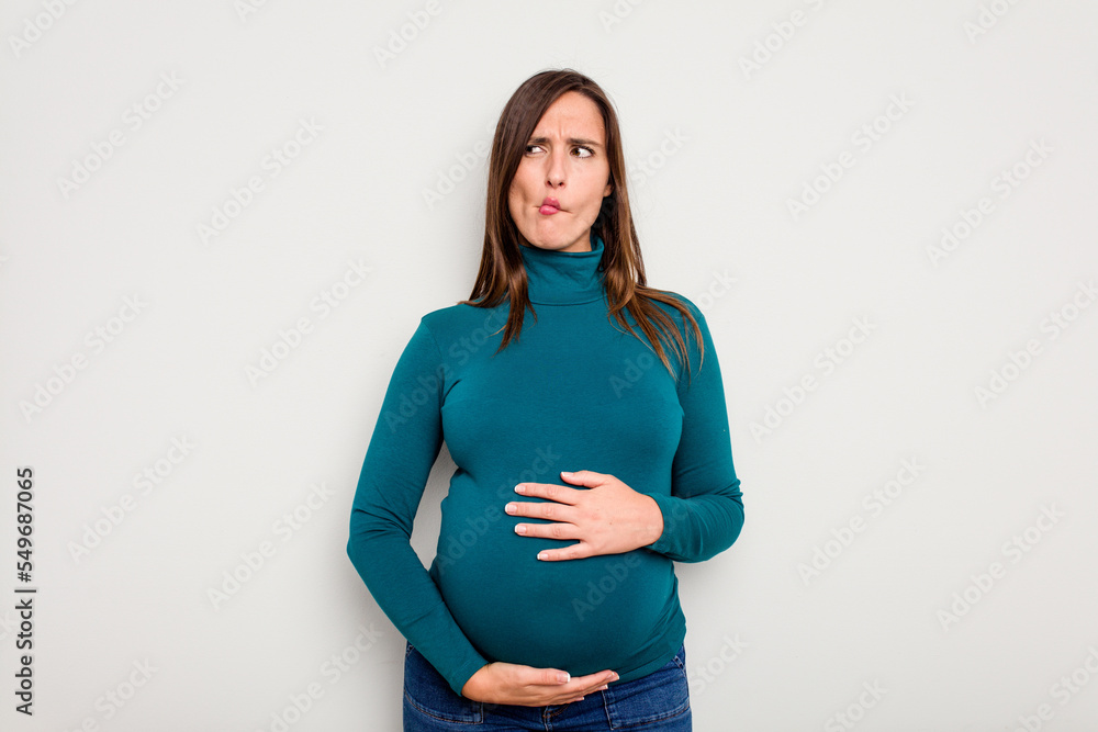 Pregnant caucasian woman isolated on white background confused, feels doubtful and unsure. Pregnant caucasian woman isolated on white background confused, feels doubtful and unsure.