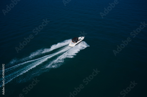 Luxury motorboat with aerial view. Top view of a white boat sailing in the blue sea.