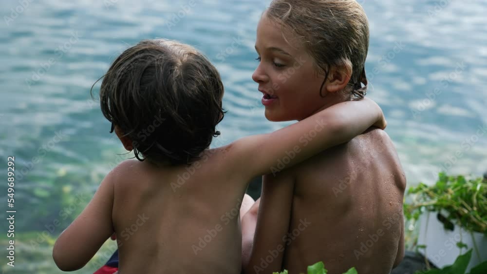 Arm in arm. Two wet children rear view embracing by lake. Brothers bonding together during summer day. Back of kids hug. Boys Friendship concept Arm in arm. Two wet children rear view embracing by lake. Brothers bonding together during summer day. Back of kids hug. Boys Friendship concept