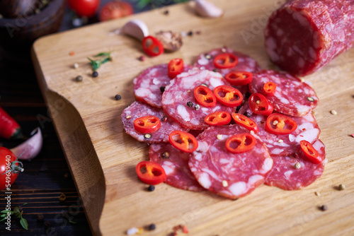 Traditional salami sausage on wooden cutting board with spices