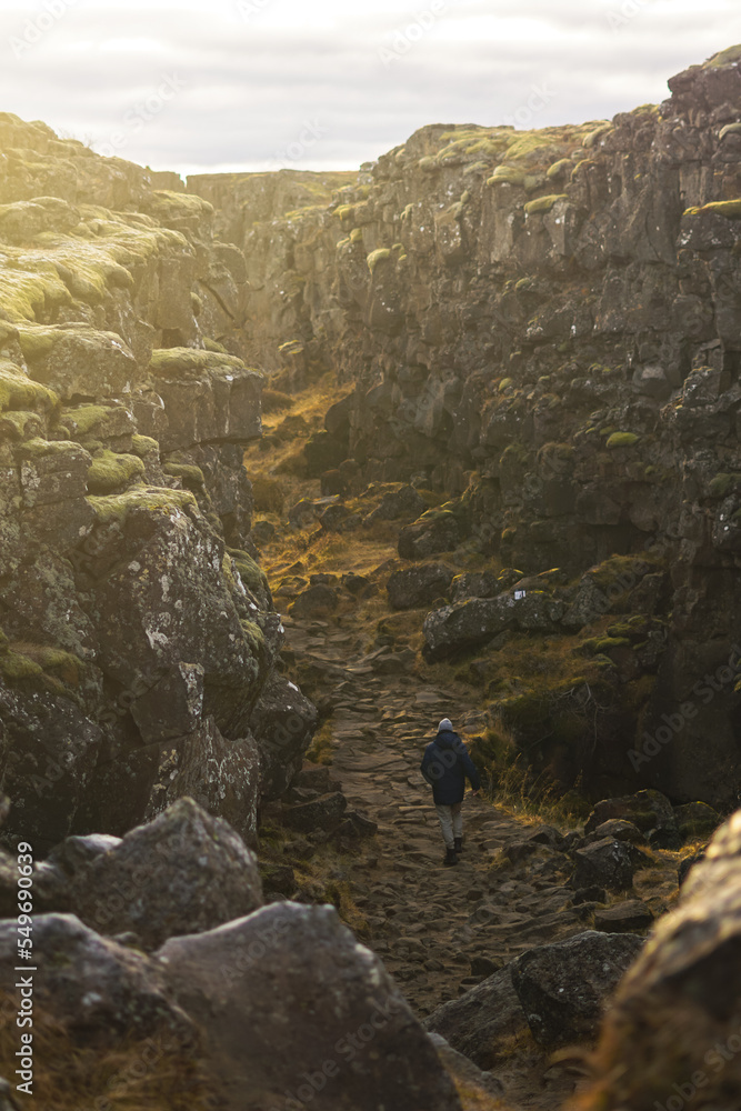 adventurous man walks on a long path between mountains in iceland