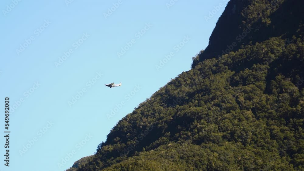 Light aircraft against blue sky and fjord cliffs in Milford Sound, New Zealand Light aircraft against blue sky and fjord cliffs in Milford Sound, New Zealand